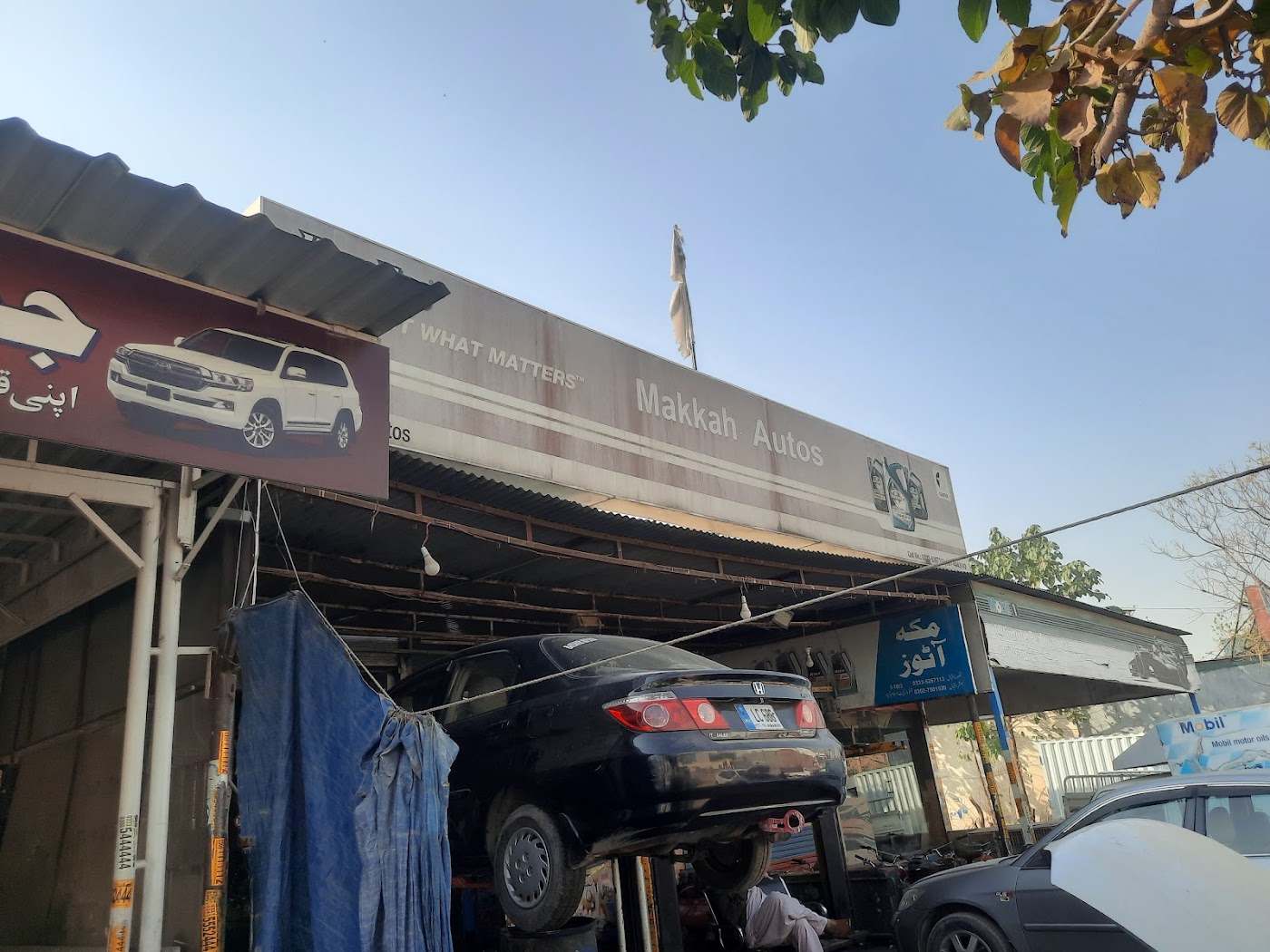 Cars raised on the lift at the Makkah Autos workshop, under the shop sign